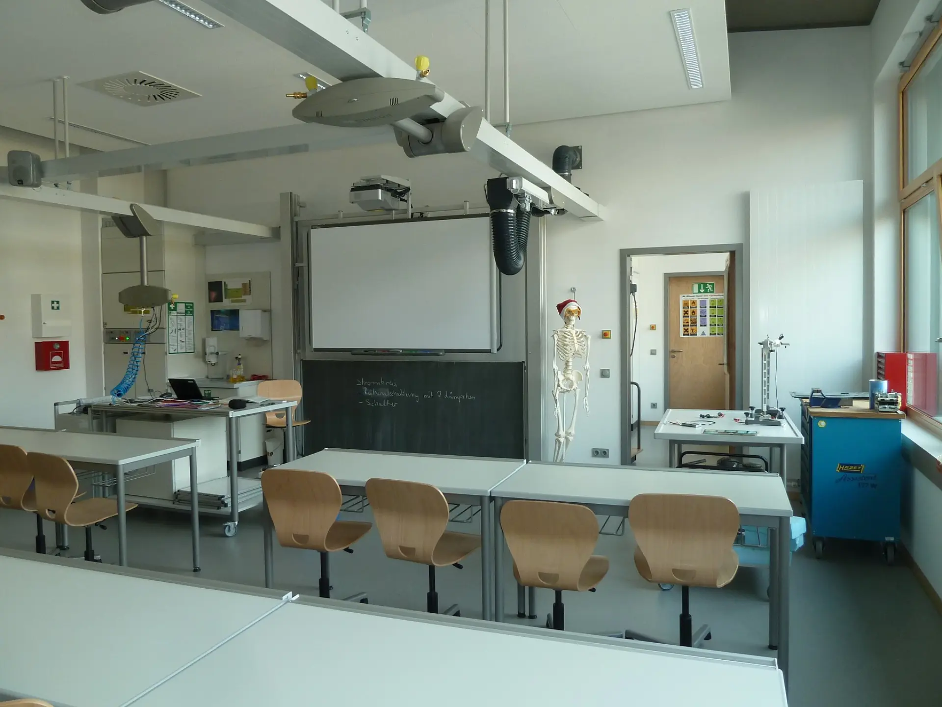 Moderner Biologie- und Naturwissenschaftsraum mit Tischen und Stühlen für die Schüler*innen, interaktiver Tafel und einem Skelett-Modell