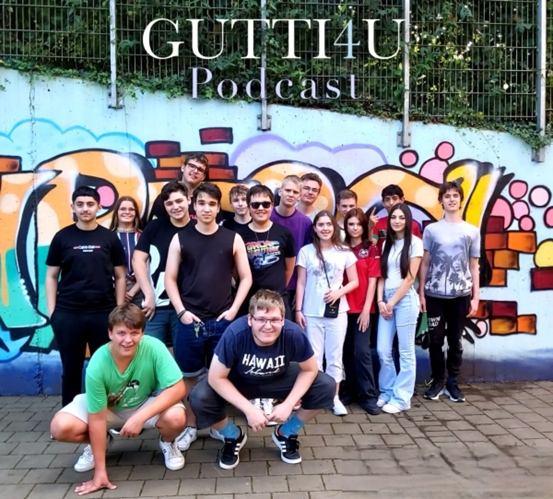 Eine Gruppe aus mehreren Schüler*innen, die das Podcast-Team bildet und vor einer bunten Graffiti-Wand steht. Über ihren Köpfen sieht man GUTTI4U Podcast geschrieben – den Namen des Schulpodcasts der LVR-Gutenberg-Schule.